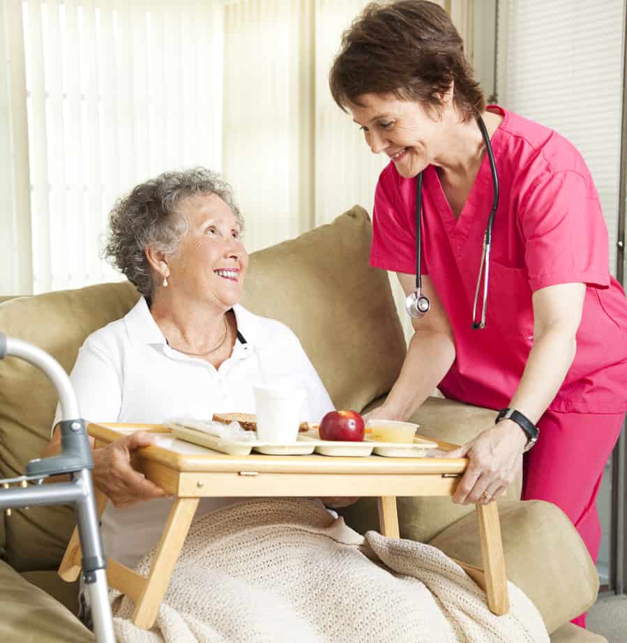 provider of home care in Belgrade handing breakfast tray to elderly patient