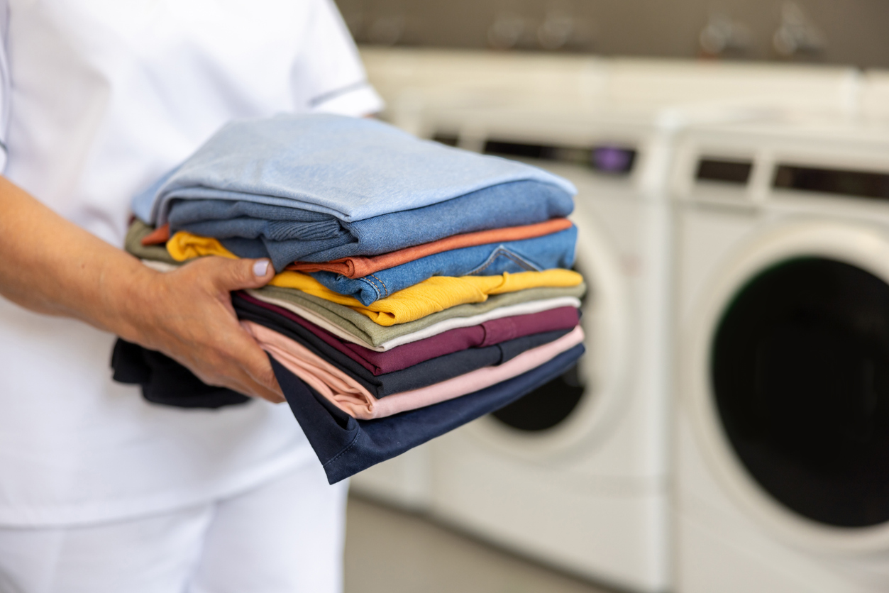 A caregiver carrying a stack of freshly folded laundry