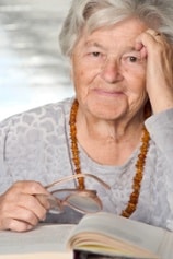 Elderly Woman Holding Glasses with a Book