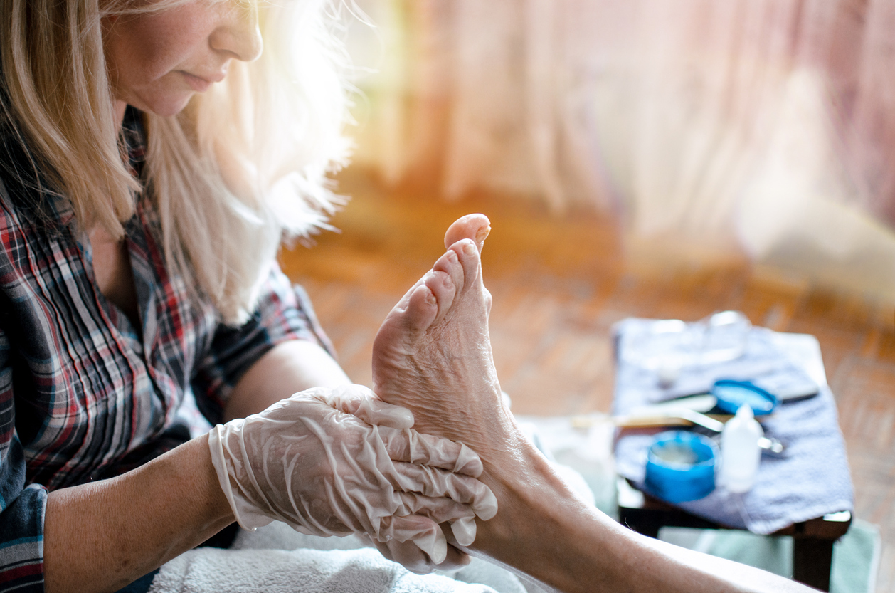 Caregiver providing gentle in-home foot care to a senior client